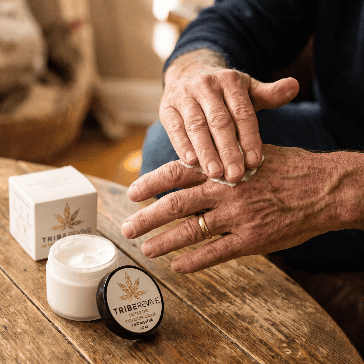 Older man massaging TribeRevive Delta 8 THC Pain Relief Cream into the back of his hand at a wooden table, the jar and box beside him