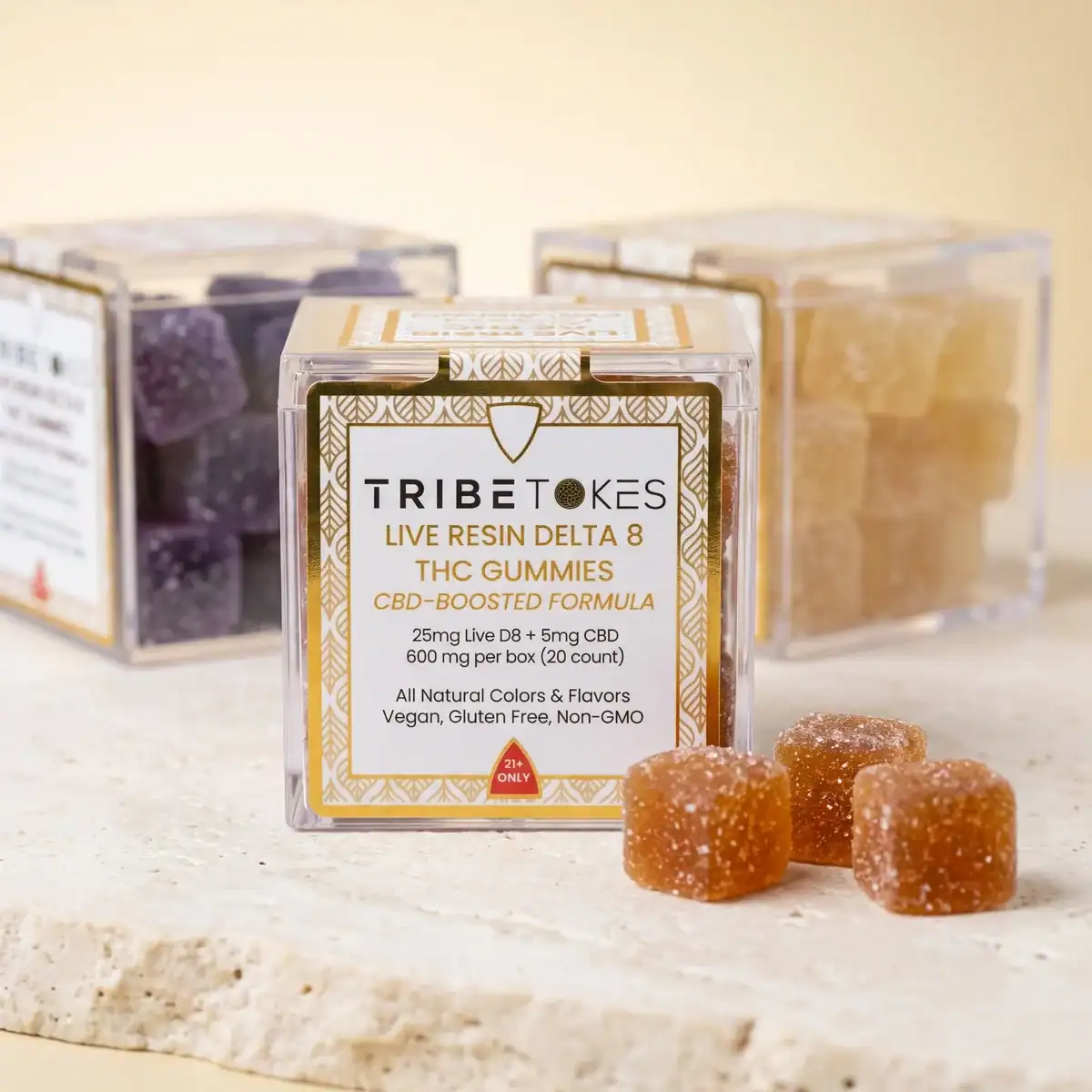 Three flavors of TribeTokes Live Resin Delta 8 THC gummies lined up, with the Strawberry cube box in front showing 25mg Delta 8 THC and 5mg CBD per piece, and two other varieties behind