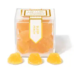 TribeTokes Sleep Peach gummies in a clear cube box with three sugar-coated peach gummies in front on a white background