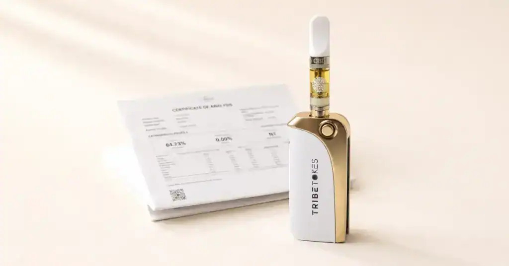 TribeTokes vape cartridge with pure amber oil beside a lab COA document on a cream background representing clean vaping with no MCT oil vegetable glycerin or Vitamin E Acetate additives