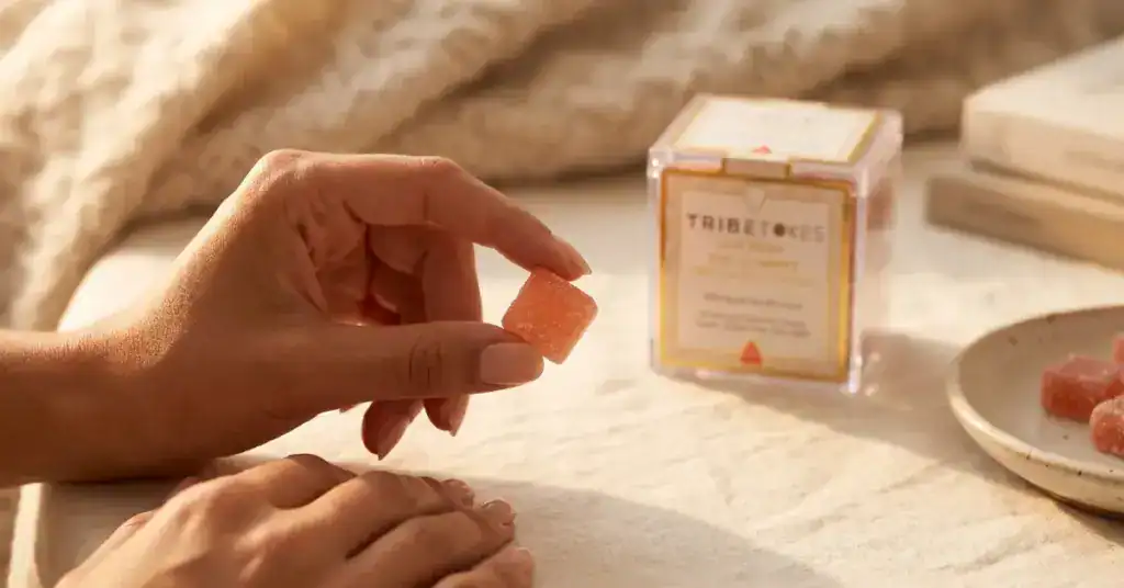 Woman holding a TribeTokes live resin gummy, illustrating the entourage effect of cannabinoids and terpenes working together