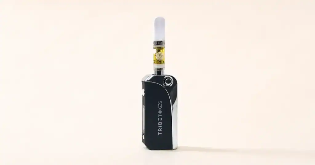 TribeTokes vape cartridge on its side showing pure amber cannabis oil through the glass chamber beside an ingredient label on a cream background representing vape ingredient transparency guide