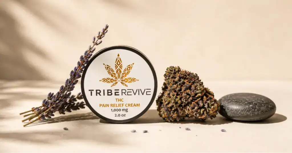 TribeRevive Delta-8 pain relief cream beside an indica hemp flower bud and lavender on a cream background representing best indica cannabis strains for pain relief and terpene effects guide