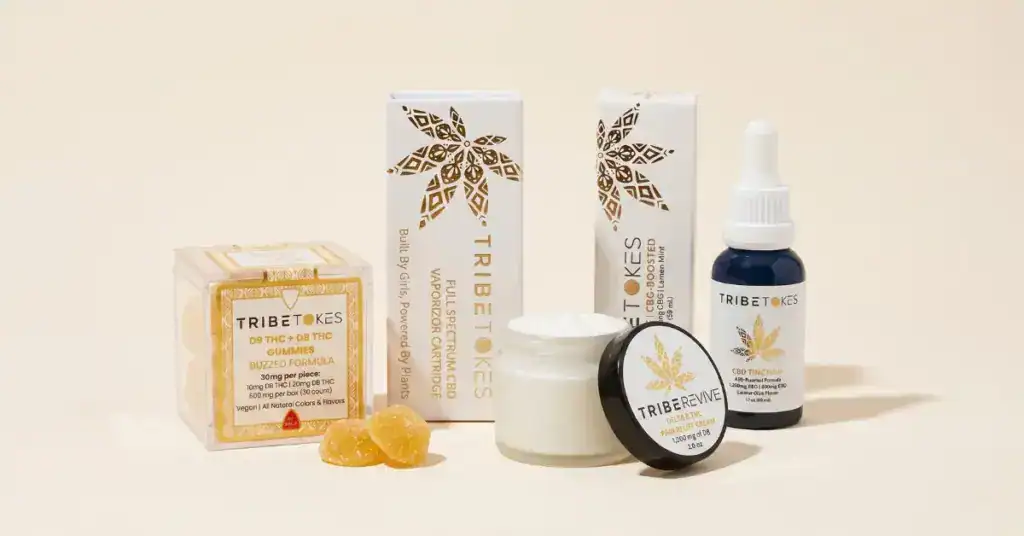 Four TribeTokes cannabis product formats arranged on a cream background: CBD vape cartridge, CBG-boosted tincture, Buzzed THC gummies, and TribeRevive Delta 8 pain cream — representing vape, tincture, edible, and topical dosing options for beginners