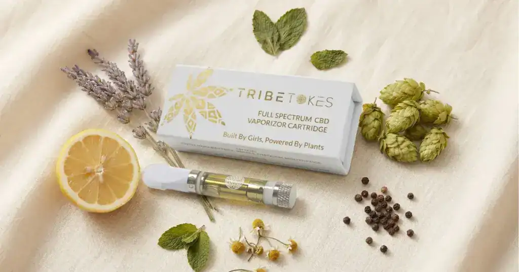 Terpene botanicals — lavender, lemon, hops, and chamomile — arranged with a TribeTokes CBD disposable vape on cream linen surface