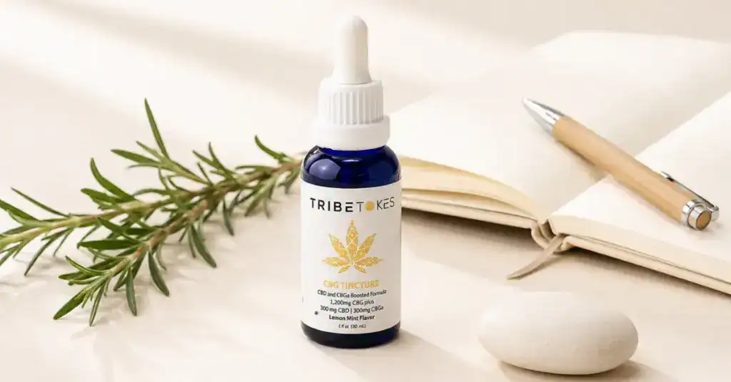 TribeTokes CBG tincture bottle with rosemary sprig and open notebook on a cream background representing CBG cannabinoid for focus energy and calm mental clarity