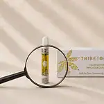 TribeTokes cannabis product with magnifying glass on cream linen — editorial flatlay representing consumer scrutiny of cannabis COA lab reports and how to spot fake or incomplete certificates of analysis
