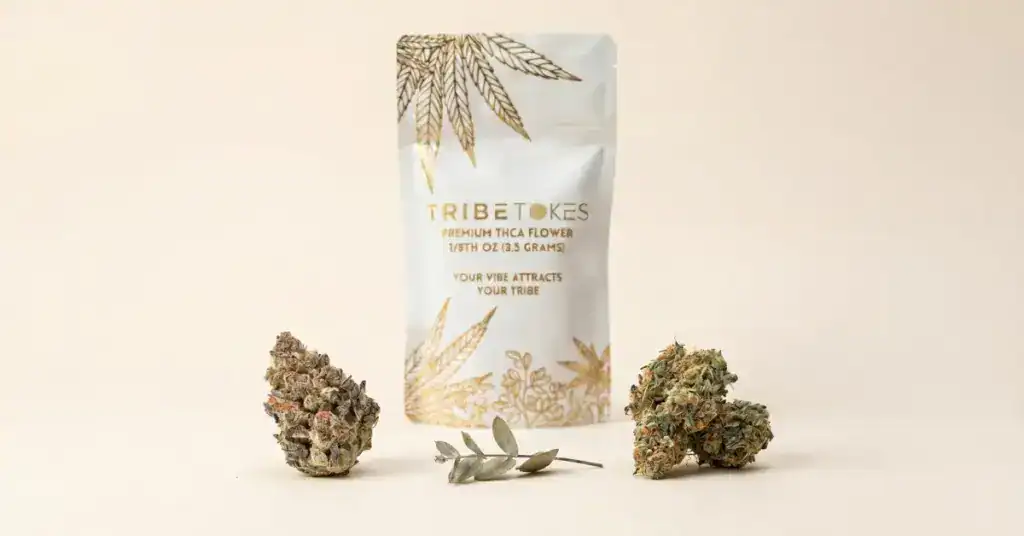 Two trichome-covered cannabis flower buds placed side by side on a cream surface with TribeTokes THCa Flower packaging in the background, illustrating the comparison between THCV and THC cannabinoids