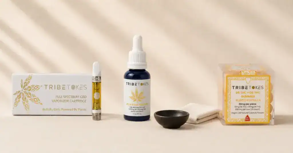 TribeTokes cannabis products flatlay on cream linen — cart, tincture, and gummies representing every-batch third-party lab testing process and COA transparency for hemp vape and edible products