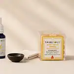 TribeTokes cannabis products flatlay on cream linen — cart, tincture, and gummies representing every-batch third-party lab testing process and COA transparency for hemp vape and edible products