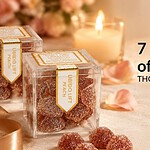 Two Libido Lift gummy boxes and sugar-coated peach gummies on cream linen beside lit candles, rose petals and a halved peach